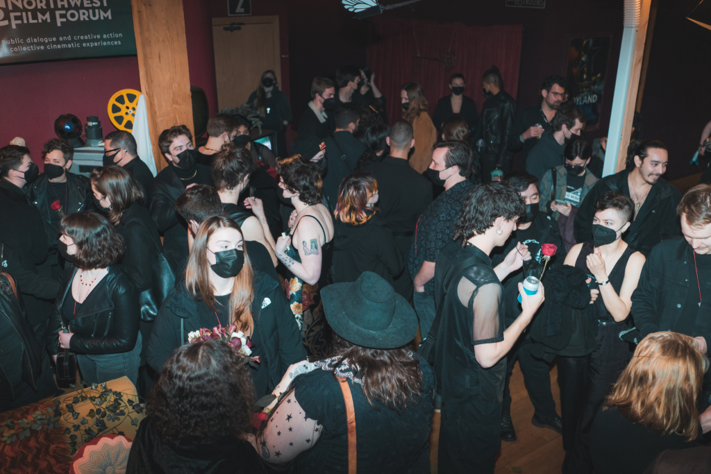 A group of people wearing all black mingling in the lobby of the building.