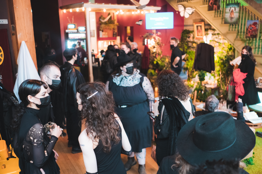 A group of people standing in a building lobby wearing all black, talking to each other.