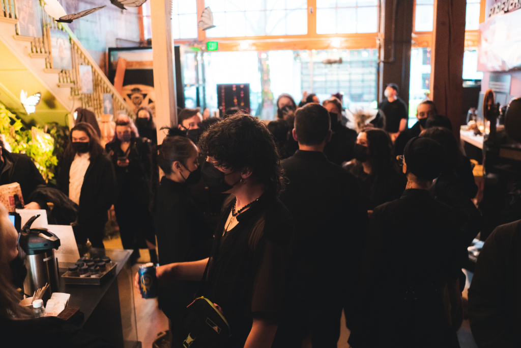 A group of people wearing all black mingling in the lobby of the building.