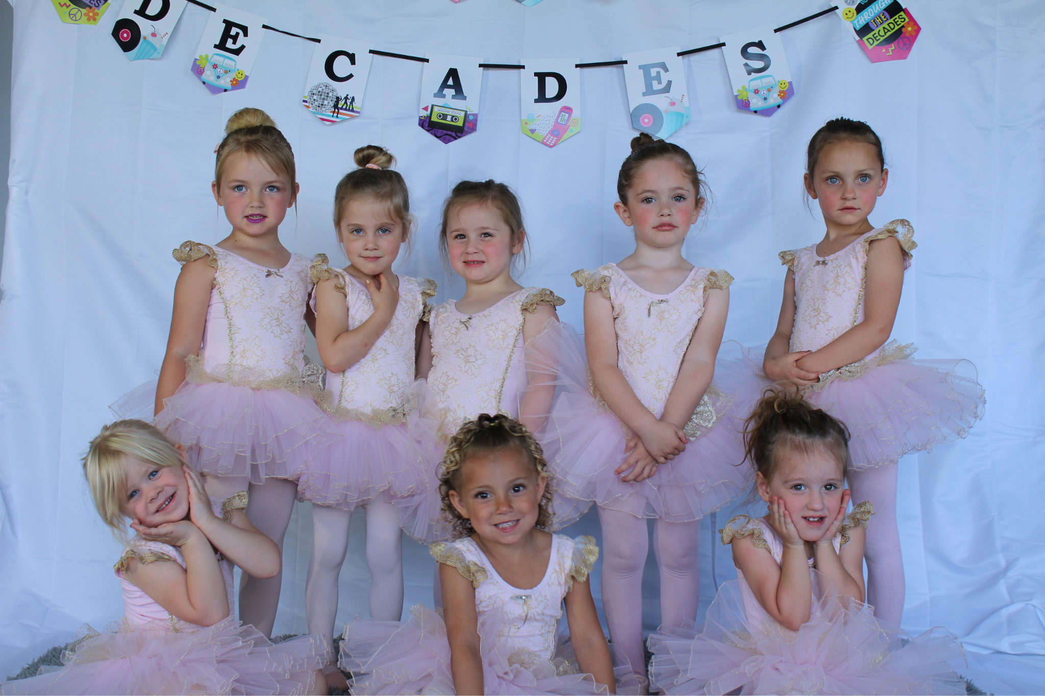 A group of young children posing their ballet pink tutus.