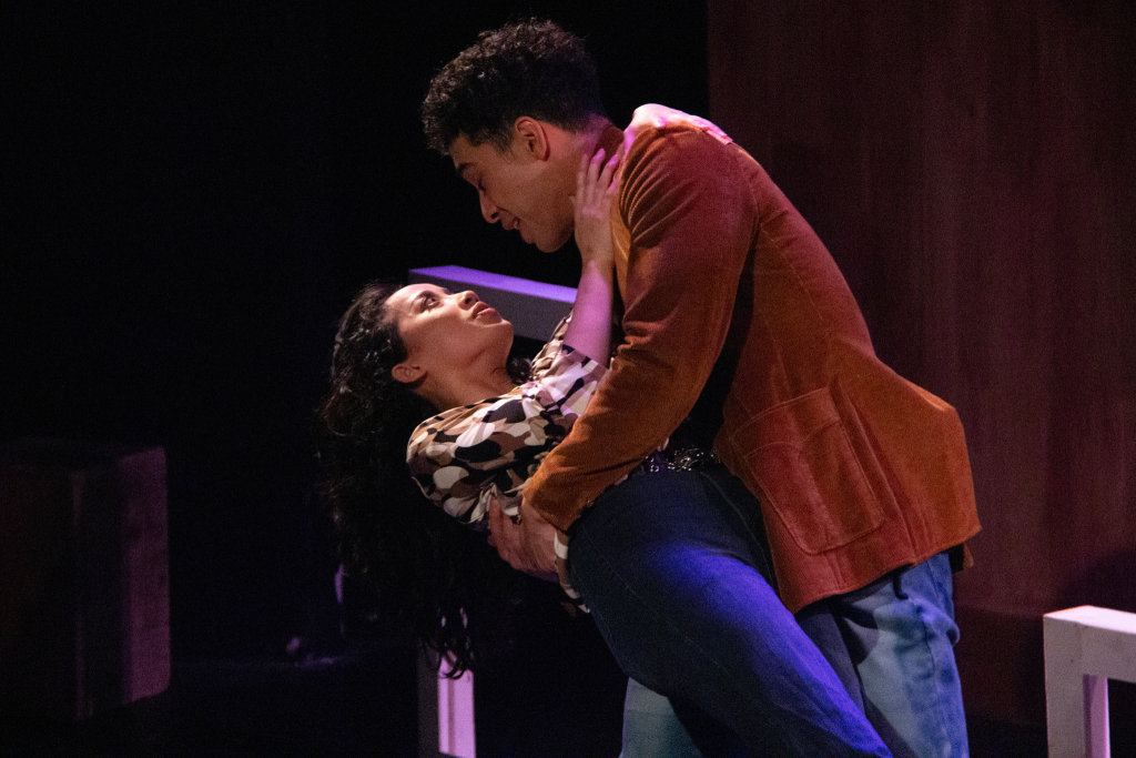 A couple mid-dance on a theater stage.