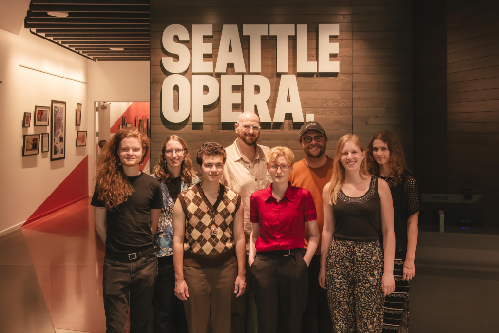 A Group of Seattle Opera staff posing for a group photo in front of the Seattle Opera sign.