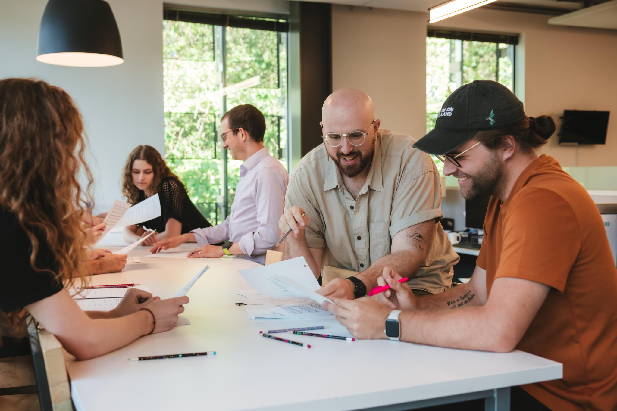 A group of people working at a table reading papers and taking notes.